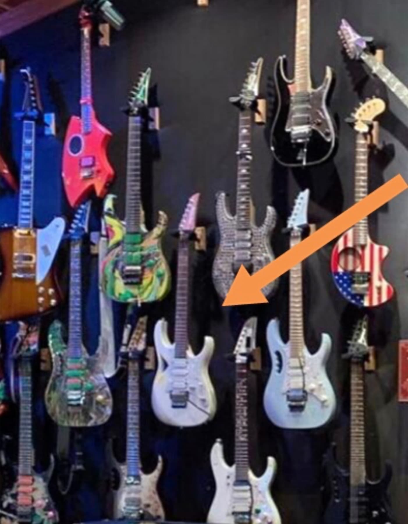 The Modern Primitive hanging among the guitars in Steve Vai's collection, marked with an arrow