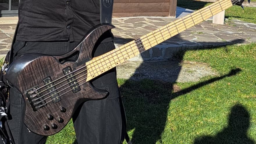 A five-string Blackhole worn outdoors, with its dark figured top and maple fretboard