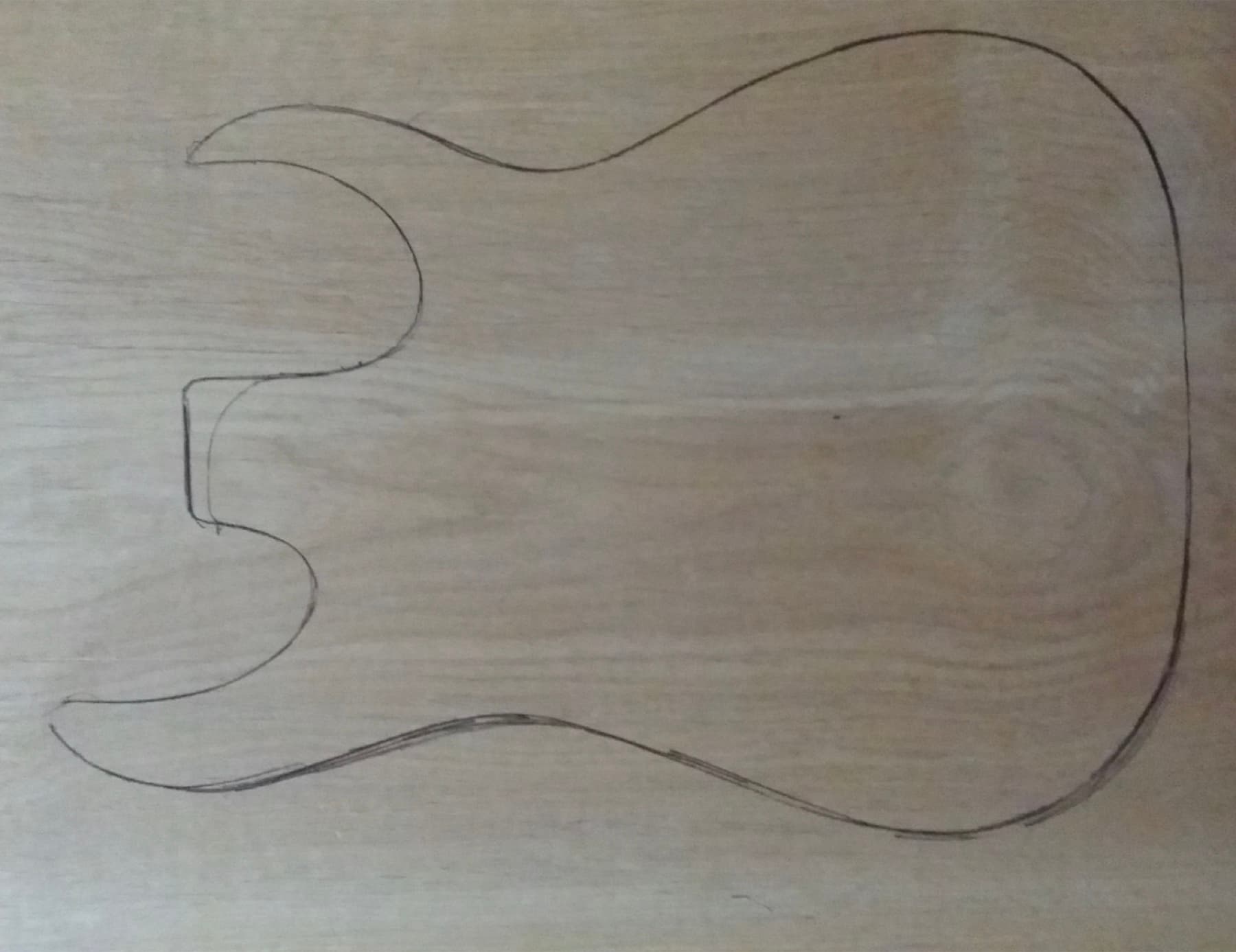 A body template resting on the bench, next to the board waiting to be cut