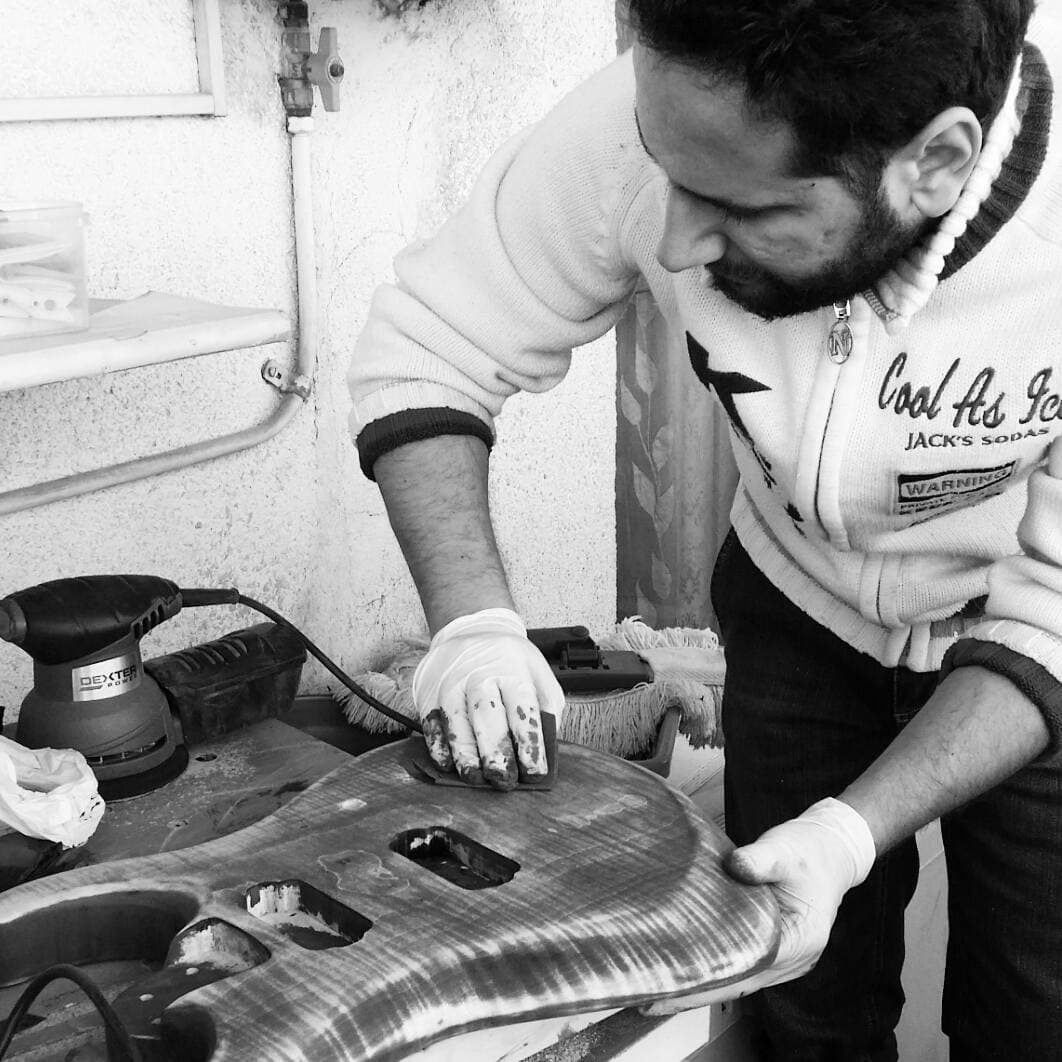 Alberto De Gattis in the workshop, in black and white, hand-sanding the body of a guitar